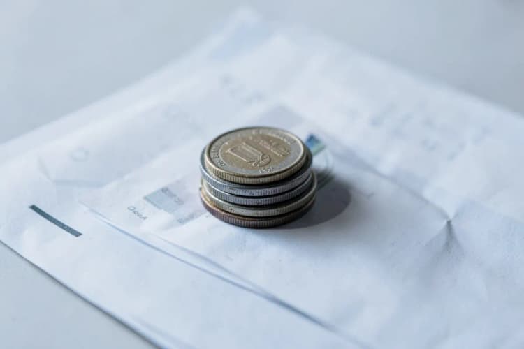 Uma pilha de moedas e notas de dinheiro em cima de um documento.