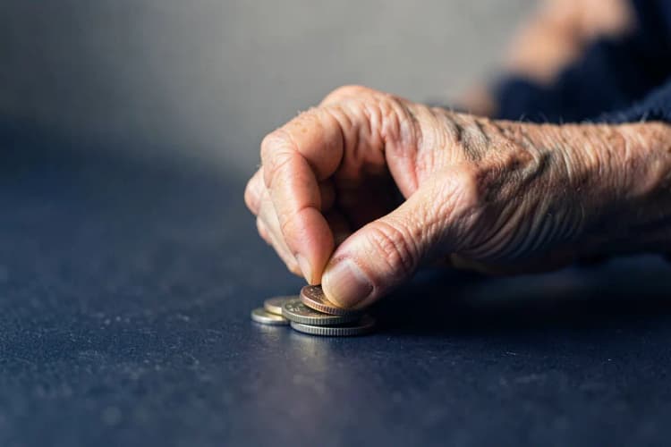 Uma pessoa idosa contando moedas em suas mãos